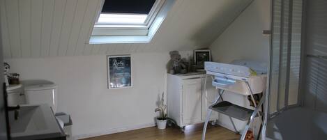 A small, tidy room with a skylight, a white cabinet, a small table, and a potted plant.