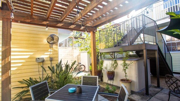 Eine Terrassengruppe mit Tisch und Stühlen, eine Pergola, Kübelpflanzen und eine Treppe zu einer erhöhten Ebene.