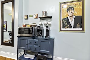Eine Küchenzeile mit Mikrowelle, Kaffeemaschine und einem gerahmten Poster an der Wand.