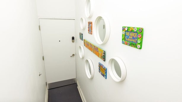 A hallway with a white door, a black floor, and several circular mirrors on the wall.