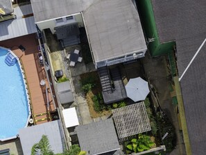 Eine Vogelperspektive eines Wohnhauses mit Schwimmbad, Terrassenmöbeln und einem kleinen Garten.