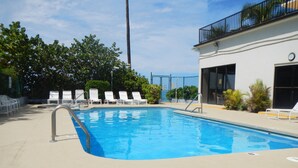 A swimming pool with white lounge chairs and a building with a balcony. - Best Kept Secret on Oahu ! (Waiʻanae)