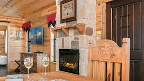 Una habitación acogedora con chimenea de piedra, paredes de madera y una puerta de madera.