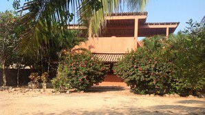 Un bâtiment doté d’un toit en tuiles, entouré d’une végétation luxuriante et d’arbustes en fleurs.
