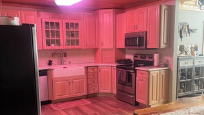 A kitchen with pink cabinets, a black refrigerator, a microwave, and a wooden table with a bench. - Hayward, Wisconsin Waterfront Cabin located on Nelson Lake, Pontoon available. (Hayward)