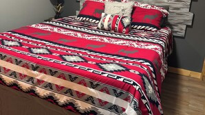 A bed with a patterned bedspread, a wooden headboard, and decorative pillows. - Hayward, Wisconsin Waterfront Cabin located on Nelson Lake, Pontoon available. (Hayward)