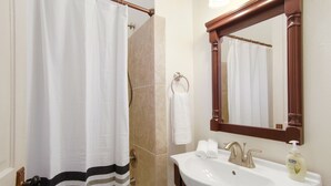 A bathroom with a shower curtain, a sink with a mirror, and a towel rack. - Large Shotgun Double In Perfect Uptown Location Near Magazine and State St. (New Orleans)