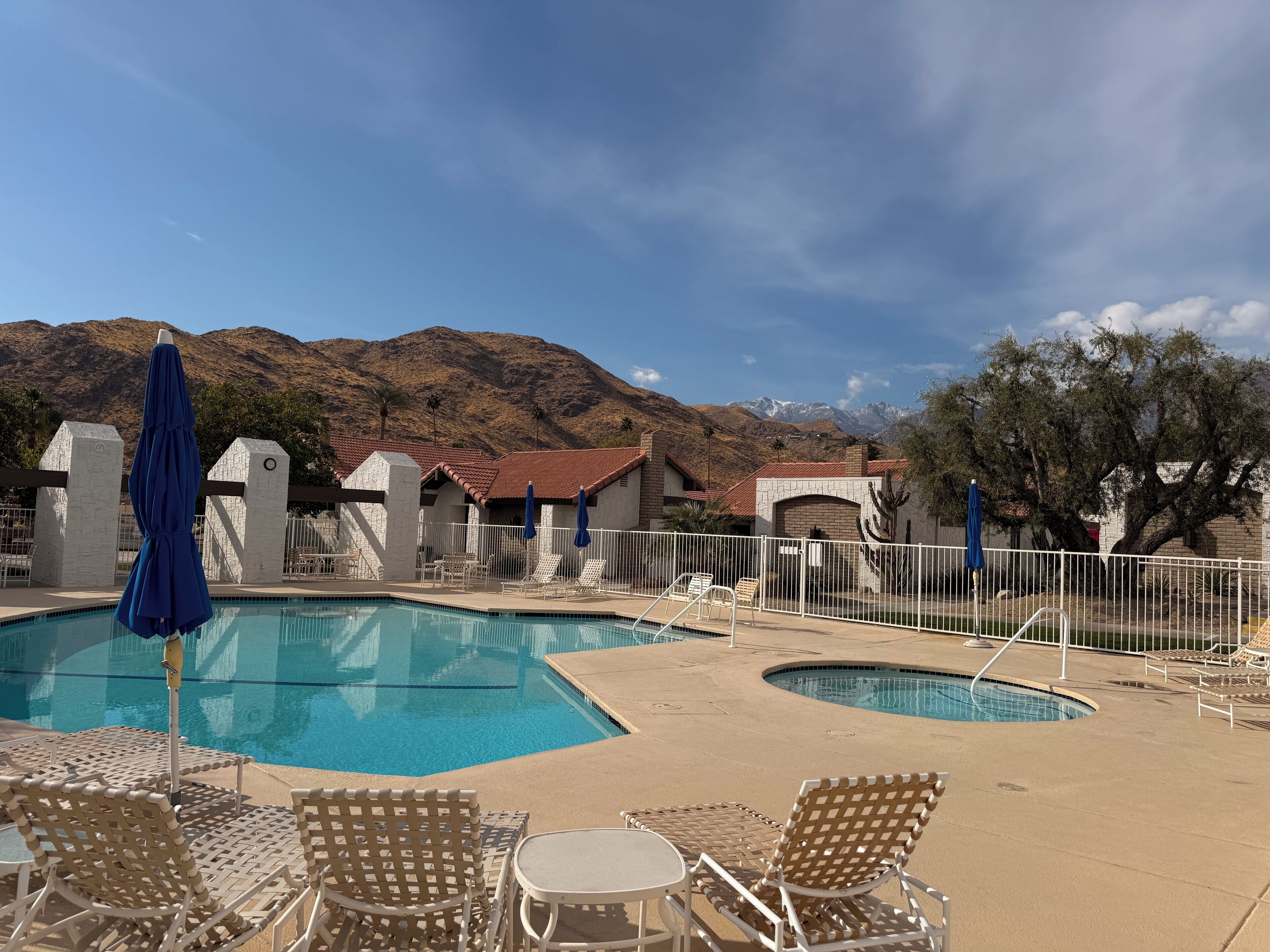 Ein Poolbereich mit zwei Pools, Liegestühlen und Sonnenschirmen.