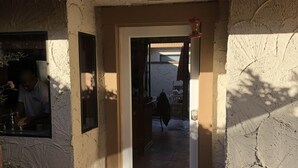 Uma entrada de edifício com telhado de azulejos, porta e janela.