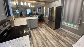 A modern kitchen with a marble countertop, stainless steel appliances, and a wooden floor. - Urban Retreat! Sauna-Updated Craftsman Private Backyard! Pet friendly! Discounts (Seattle)