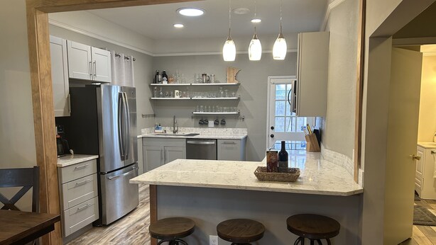 A modern kitchen with a central island, bar stools, and a refrigerator. - Urban Retreat! Sauna-Updated Craftsman Private Backyard! Pet friendly! Discounts (Seattle)