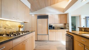 A modern kitchen with wooden cabinets, a stainless steel refrigerator, and a built-in dishwasher. - Inspired by a view of the Sea (Sea Ranch)