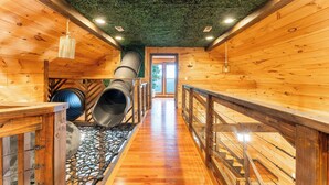 A wooden interior with a central staircase, a green artificial ceiling, and a view to the outside. - Big Time Hill Cabin with an indoor pool, hot tub, & great views! (Bryant)