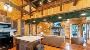 A rustic cabin interior with a kitchen, dining area, and living room. - Big Time Hill Cabin with an indoor pool, hot tub, & great views! (Bryant)