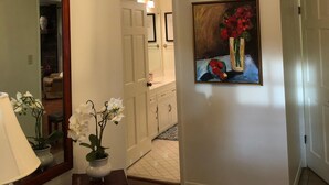 A hallway with a ceiling fan, a painting of flowers, a mirror, and a door leading to another room. - Fishing Tournaments, Auburn Games (Alexander City)