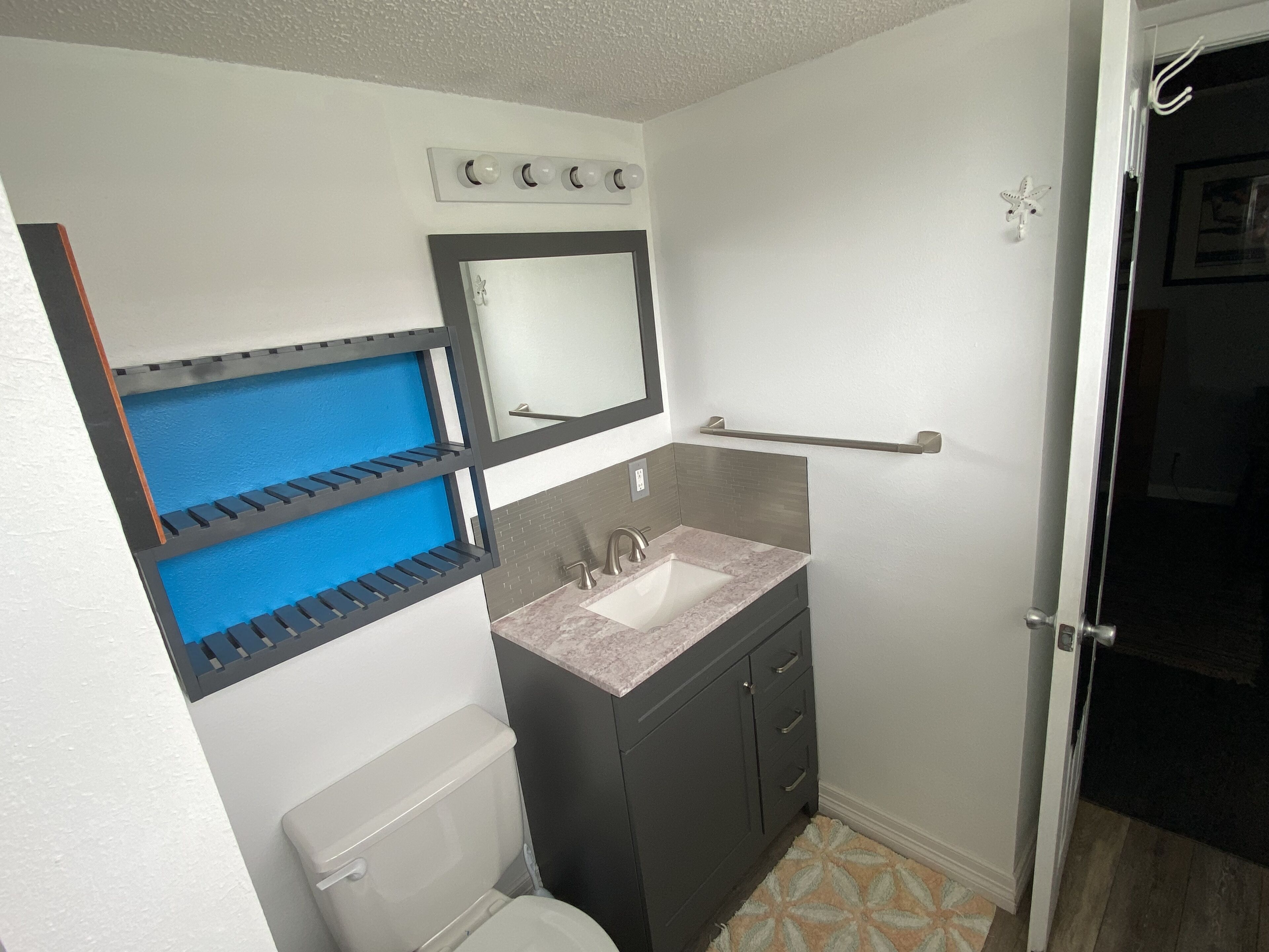 A bathroom with a toilet, sink, mirror, and towel rack.
