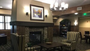 A cozy lobby with striped armchairs, a fireplace, a bookshelf, and a dining area. - Enjoy the Summer at Granby Ranch.  Golf, Bike, Hike, Fish the Fraser River! (Granby)
