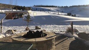 A snow-covered ski slope with a chairlift, a small building, and a fire pit area. - Enjoy the Summer at Granby Ranch.  Golf, Bike, Hike, Fish the Fraser River! (Granby)