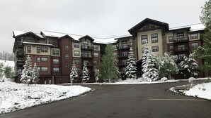 A multi-story hotel with a central courtyard and snow-covered trees. - Enjoy the Summer at Granby Ranch.  Golf, Bike, Hike, Fish the Fraser River! (Granby)