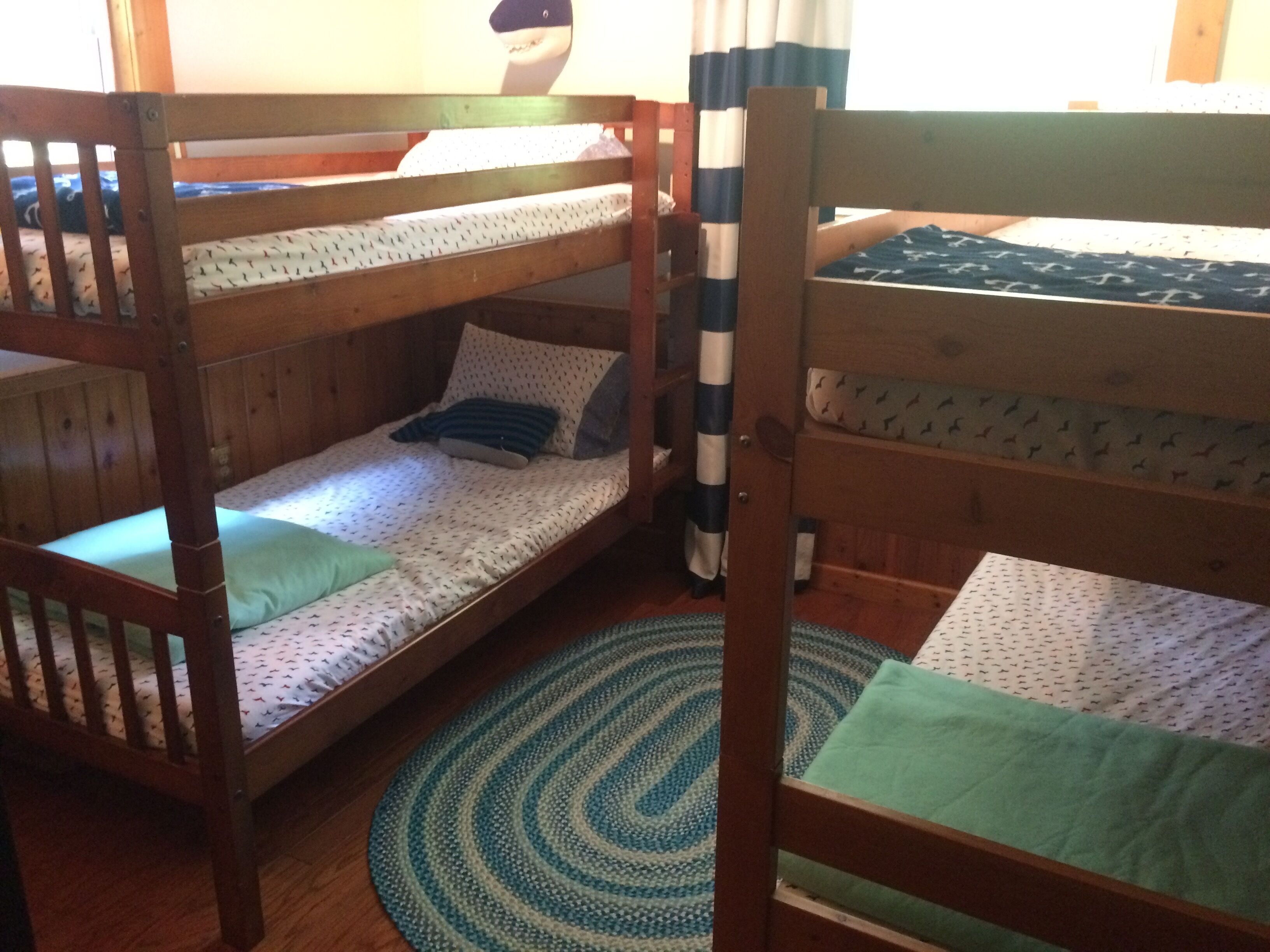 A bunk bed room with a wooden floor, a patterned rug, and a curtain.