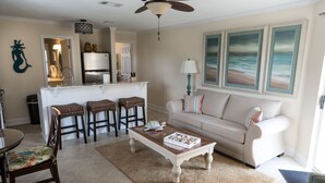 Una sala de estar con un sofá color beige, una mesa de centro y un comedor con una silla y una mesa.