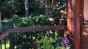 A wooden deck with a railing, surrounded by lush greenery and trees.