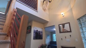 A multi-level interior with a staircase, a mounted animal head, and a mirror on the wall.