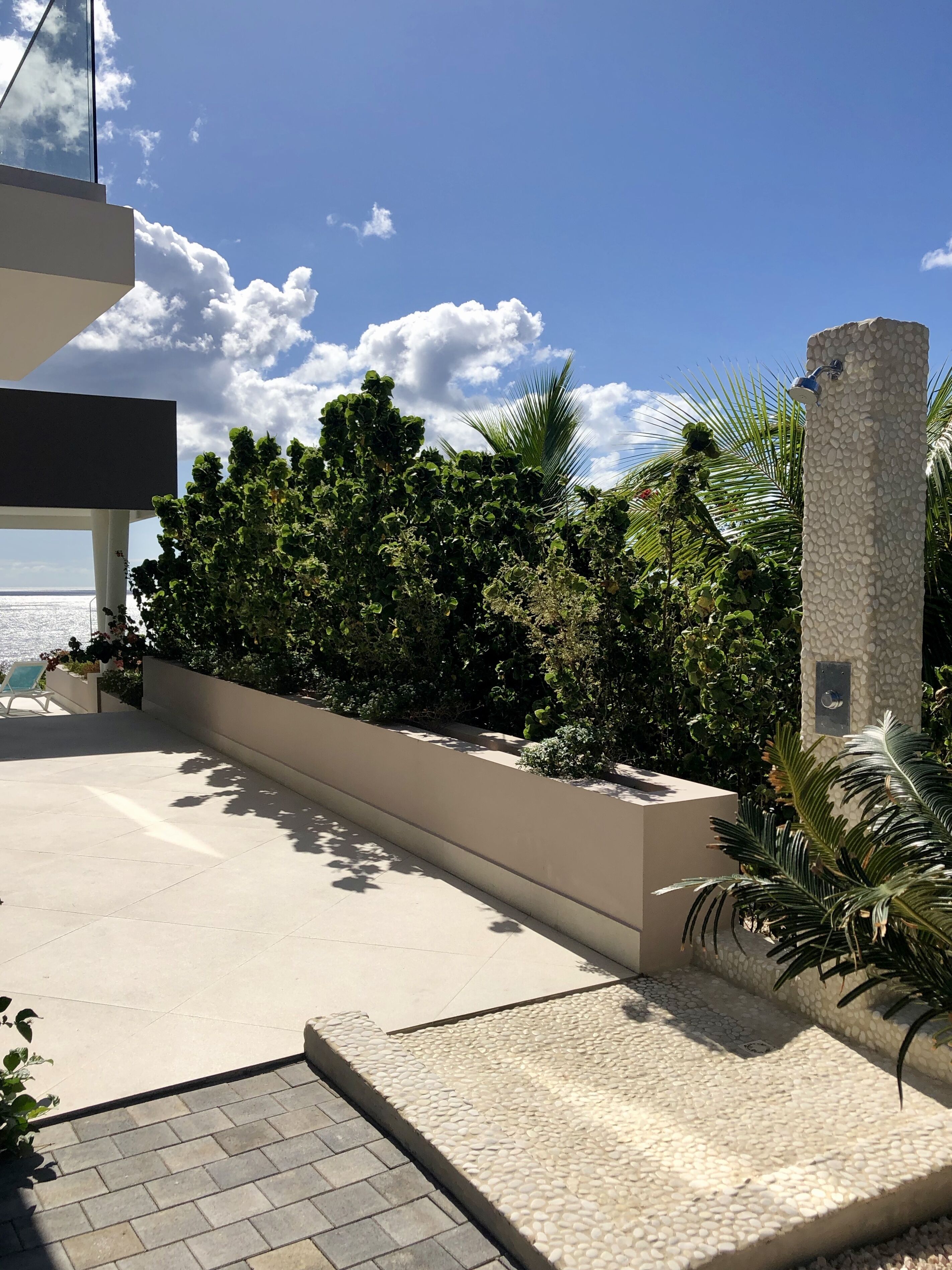 A modern outdoor area with a seating area, a water feature, and lush greenery.