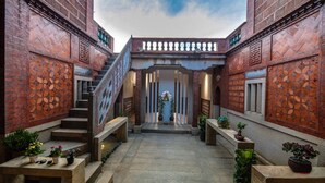 A courtyard with a central staircase, potted plants, and a decorative wall. - Kinmen redbrick houses across Hope (Xiamen)