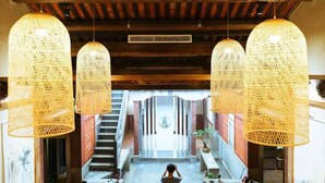 A spacious interior with a staircase leading to a central area, featuring large woven hanging lights and a visible ceiling fan. - Kinmen redbrick houses across Hope (Xiamen)