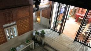 A spacious courtyard with a tiled floor, a stone bench, and potted plants. - Kinmen redbrick houses across Hope (Xiamen)