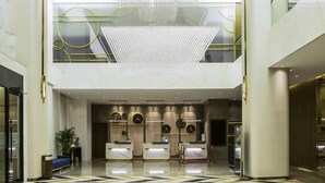 A modern hotel lobby with a reception desk, a chandelier, and a high ceiling. - Mercure Harbin Songbei (Harbin)