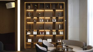 A modern lobby with a wooden bookshelf, seating area, and a small table with a bottle. - Mercure Harbin Songbei (Harbin)