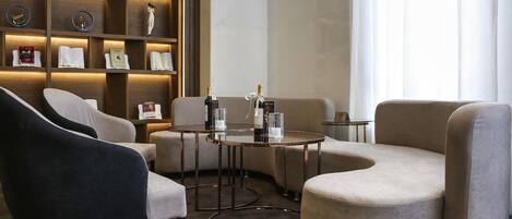 Un área de descanso moderna con un sofá, sillones, una mesita y una estantería decorada con objetos.