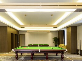 Una mesa de billar en una habitación de diseño moderno, con iluminación empotrada y piso alfombrado.