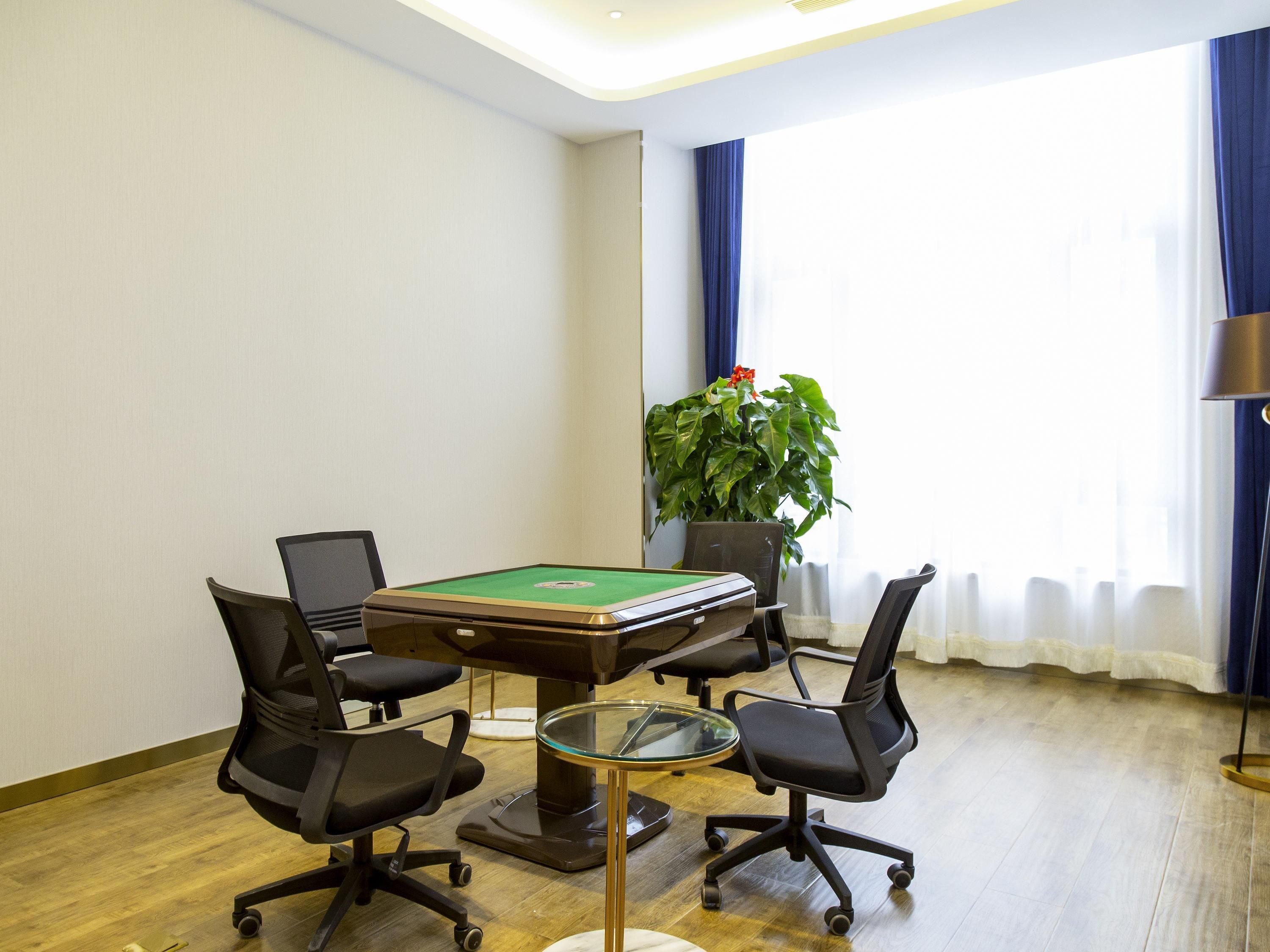 A conference room with a pool table, four office chairs, a potted plant, and a lamp.