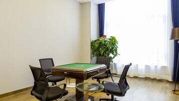 A conference room with a pool table, four office chairs, a potted plant, and a lamp.
