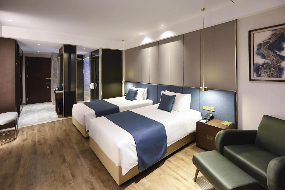 Una habitación de hotel con dos camas, un escritorio, una silla y un baño.