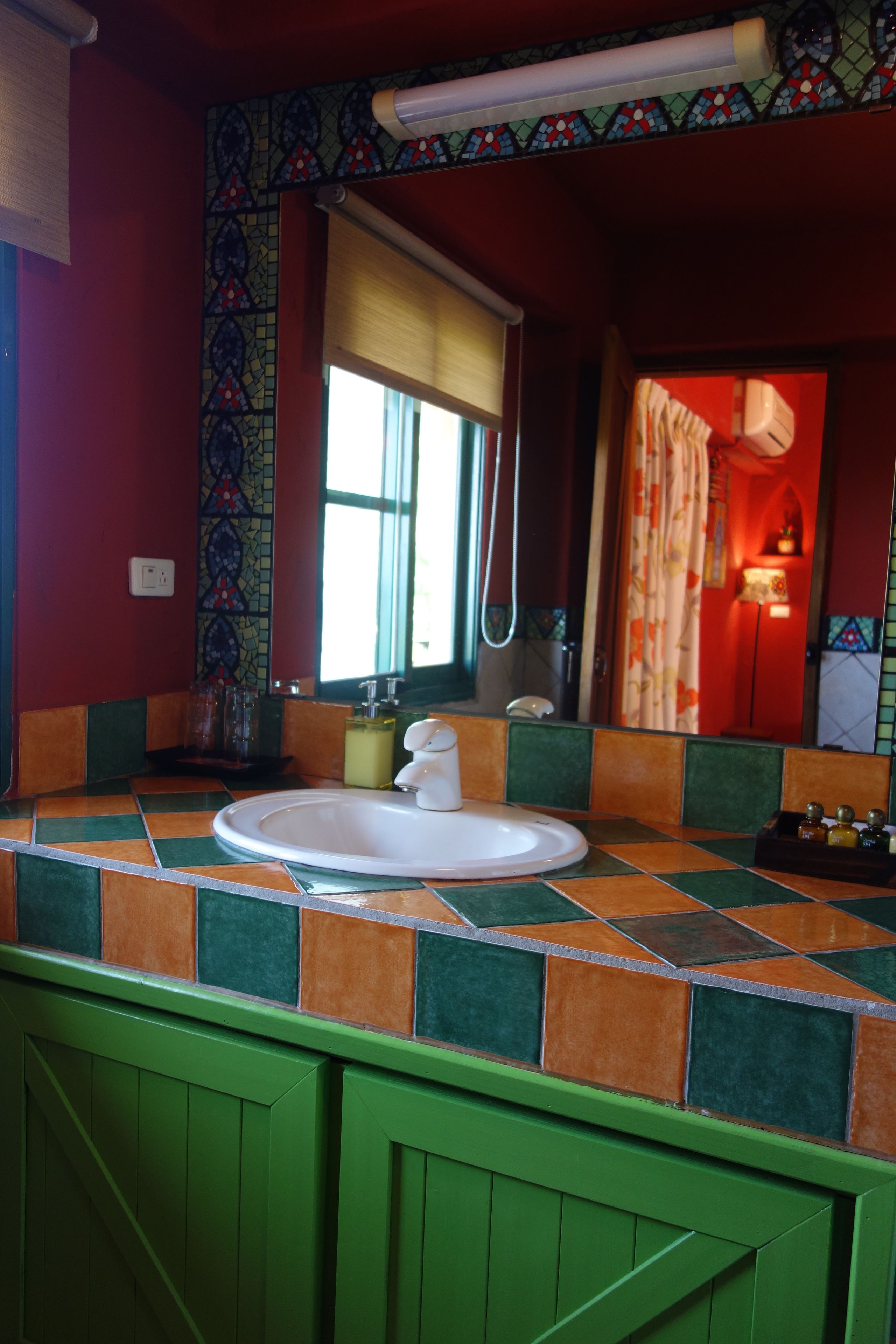 A bathroom with a tiled sink, a mirror, and a shower.