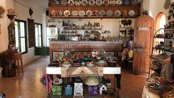 A room with a central table displaying various decorative items and a wall with shelves of plates and ceramics.