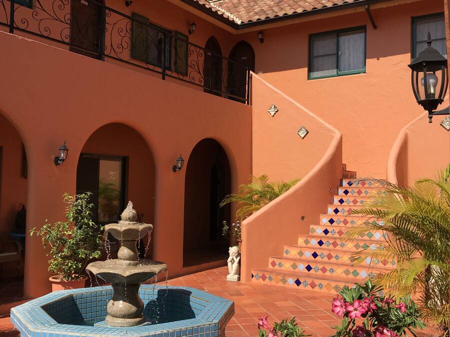 Un patio con una fuente, escalones de cerámica y plantas en macetas.