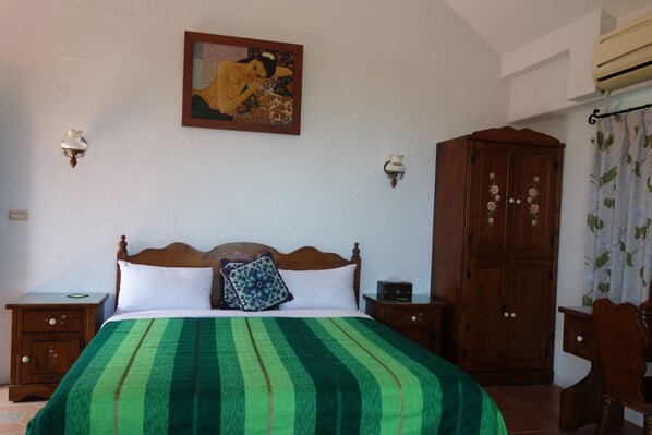 Un dormitorio con cama, mesitas de noche, un armario y un cuadro en la pared.