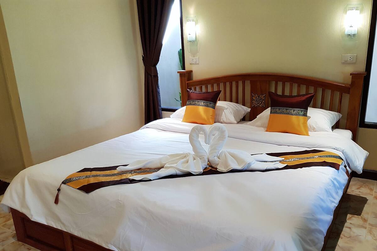 A hotel room with a large bed, two bedside tables, a wooden headboard, and a wall-mounted light fixture.