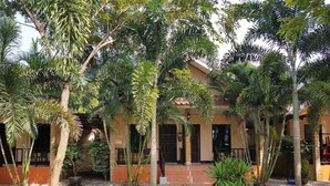 Un edificio con un patio techado, rodeado de árboles y vegetación.