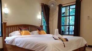 Una cama bien hecha con sábanas blancas, un cabecero de madera y almohadones decorativos.