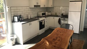 Moderni keittiö, jossa on valkoiset kaapit, kaasuliesi, mikroaaltouuni, leivänpaahdin ja jääkaappi.