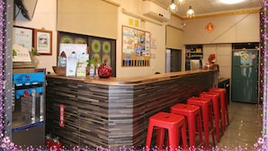 A bar area with a counter, red stools, and a refrigerator. - Da Feng Homestay (Liuqiu)