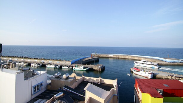 A marina with boats docked, a pier, and a view of the sea. - Da Feng Homestay (Liuqiu)