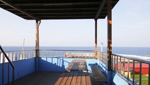 A wooden deck with a view of the sea and a pier in the background. - Da Feng Homestay (Liuqiu)