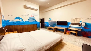 A hotel room with a bed, a TV, a desk, and a wall mural of ocean and marine life. - Da Feng Homestay (Liuqiu)